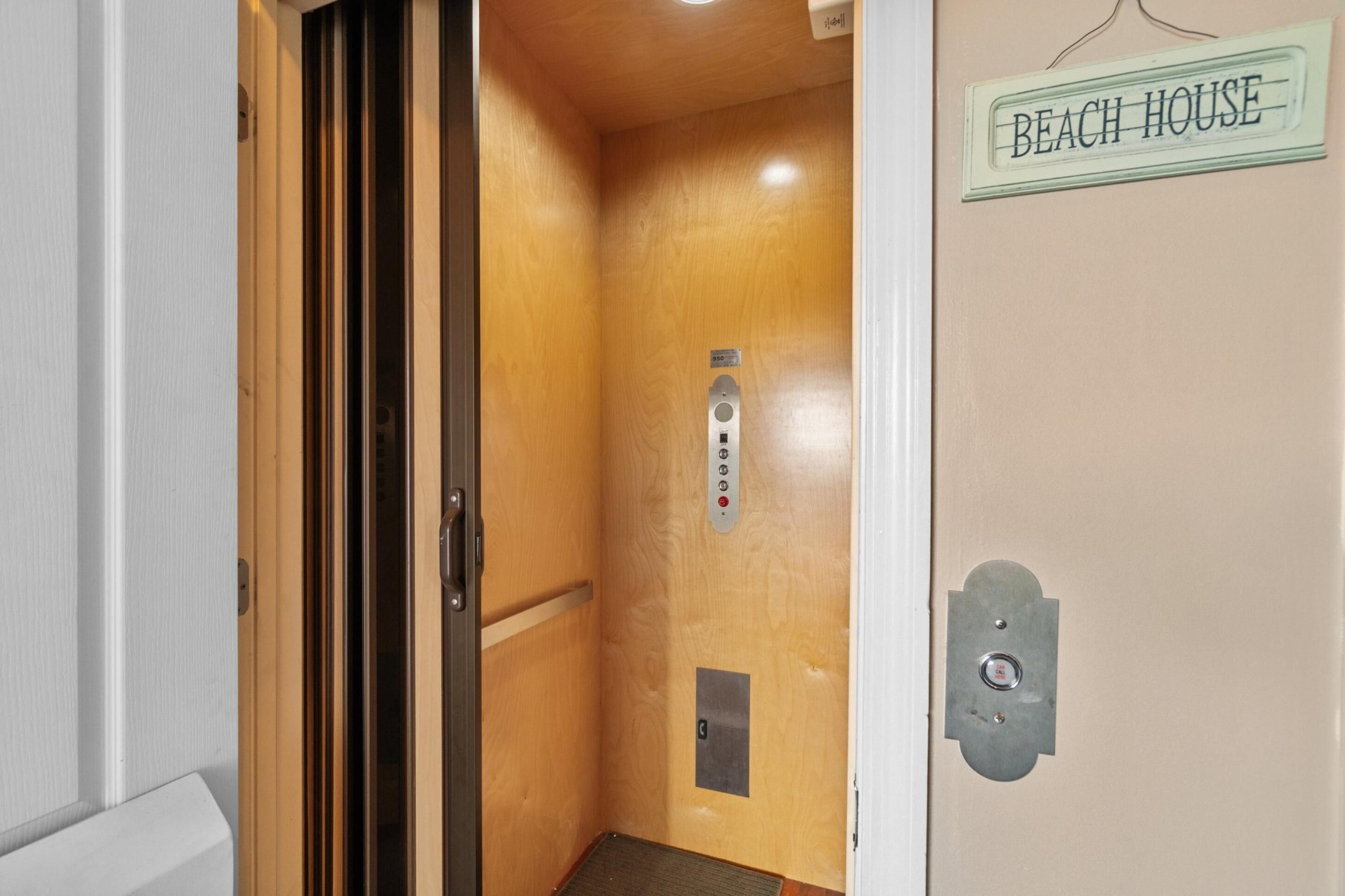 Un ascensor con un cartel que dice 'BEACH HOUSE' y un panel de control con botones.