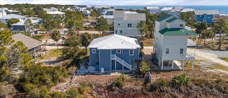 Et kystnært boligområde med huse i forskellige arkitektoniske stilarter, herunder et markant hus med blåt tag og et hvidt hus med grønt tag.