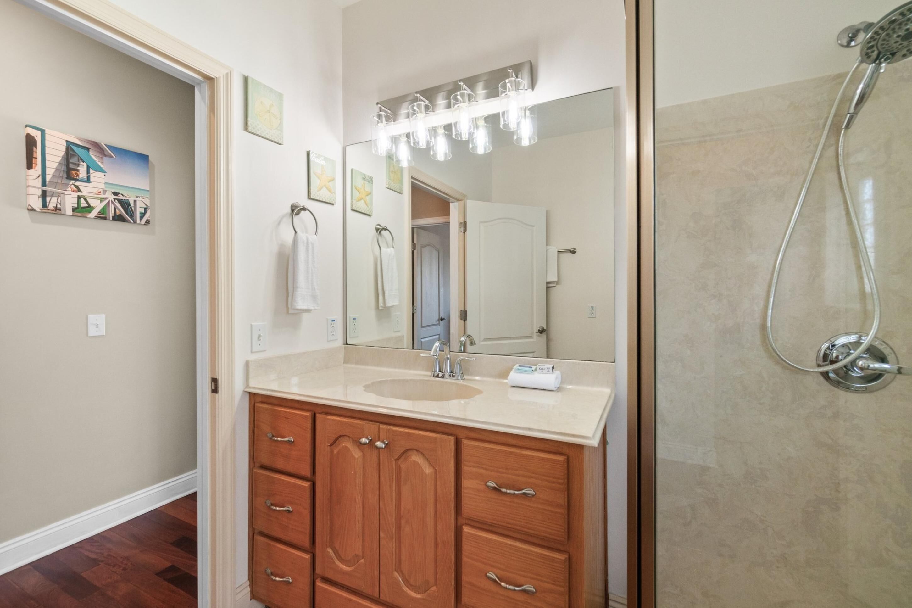 Un baño con tocador de madera, un espejo grande y una ducha.