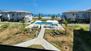 A pool area with lounge chairs and a view of the beach.
