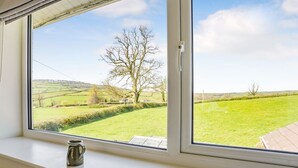 A window with a view of a rural landscape, including fields and trees. - Pant Y Cwtsh (Kidwelly)