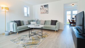 Un salon moderne avec un canapé vert clair, une table basse ronde et un téléviseur à écran plat.