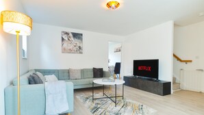 Un salon moderne avec un canapé, une table basse, un téléviseur et une lampe sur pied.