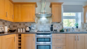Cocina moderna con armarios de madera, electrodomésticos de acero inoxidable y un ventanal que proporciona luz natural.