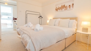 A modern bedroom with a large bed, a bedside table with a lamp, and a view of the outside.