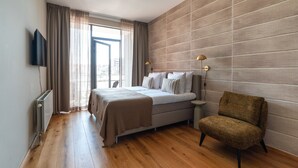 Una camera da letto con un letto, una sedia, una televisione e una finestra con tende.
