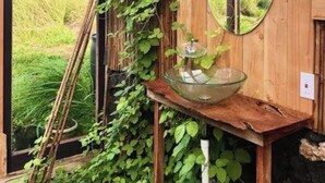 A rustic wooden cabin with a glass door, a wooden bench with a glass bowl, and a mirror on the wall.