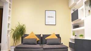 Un salon moderne avec un canapé, une plante en pot et une œuvre d’art encadrée accrochée au mur.