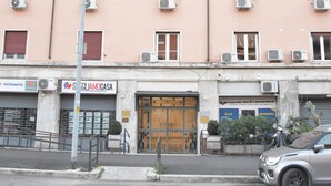 Un immeuble à plusieurs étages doté de climatiseurs, un magasin fermé avec une enseigne et une voiture garée.