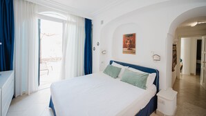 A hotel room with a bed, a desk, and a view of the outside. - Villa Pietraserena by Elite Villas (Capri)