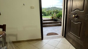 A hallway with a tiled floor, a door leading outside, and a small outdoor area with plants. - Villa Eden 2' Sea + Free Parking (Sardegna)