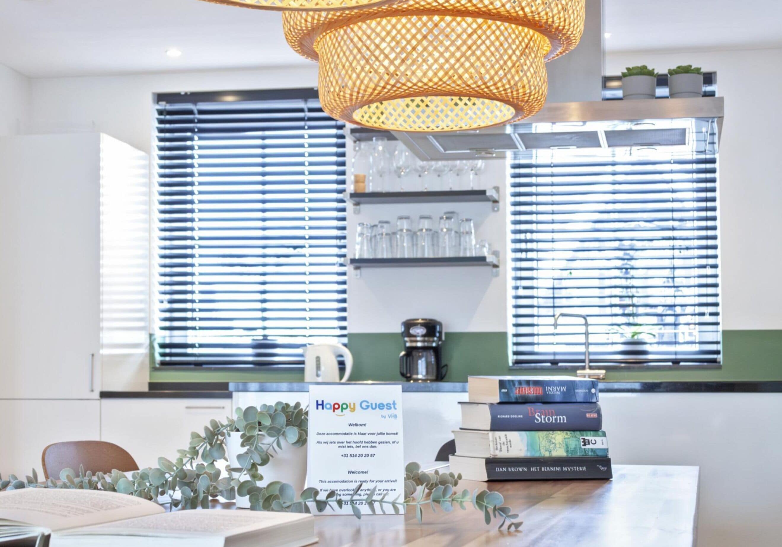 A hotel reception area with a 'Happy Guest' sign, a coffee machine, and a stack of books on the counter.