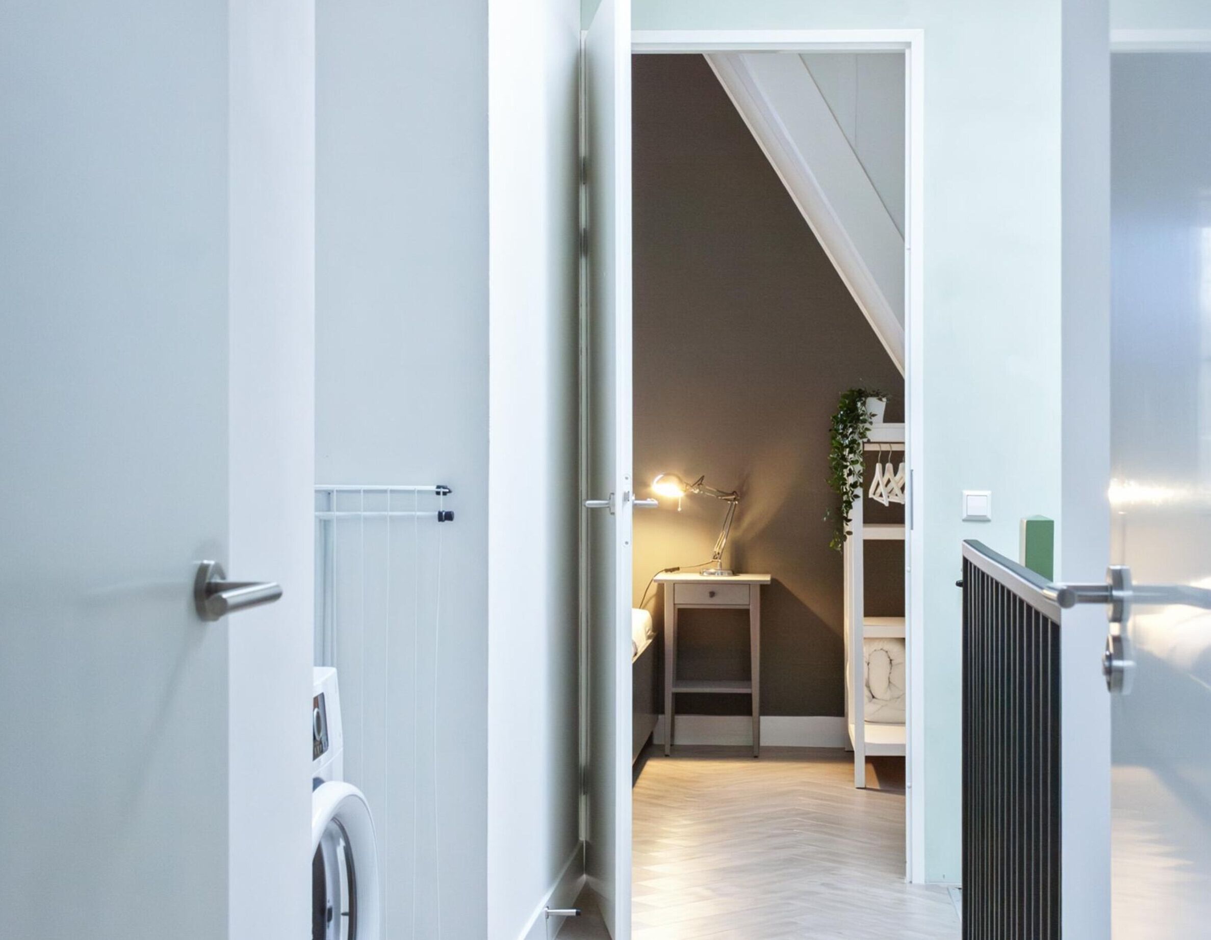 Un appartement moderne doté d’un espace buanderie, d’un bureau avec une lampe et d’un escalier menant à un autre niveau.