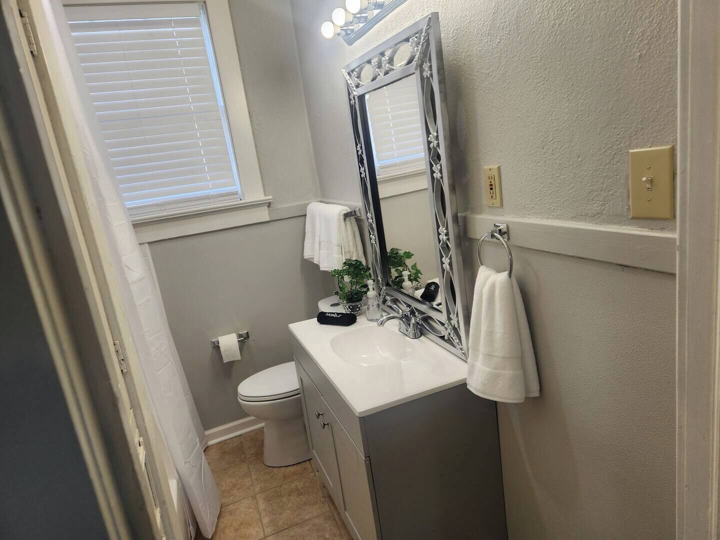 Un bagno con un lavandino bianco, un water e uno specchio grande con cornice decorativa.