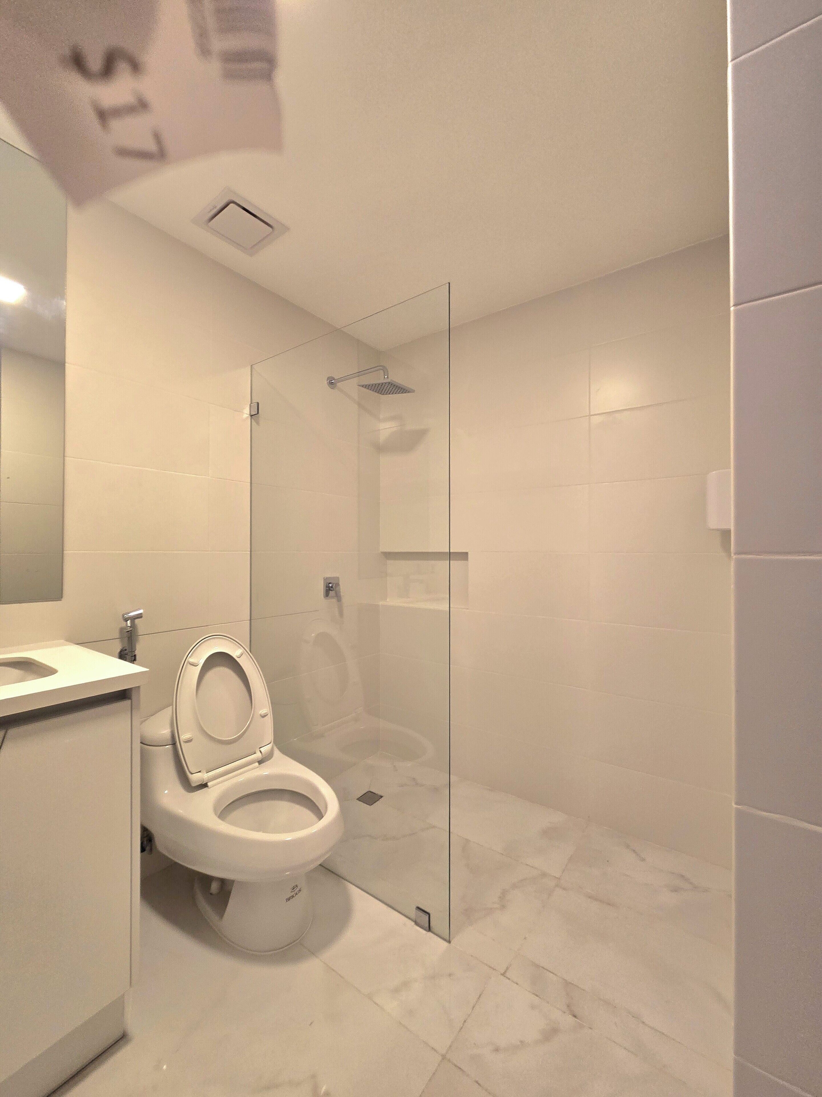 Une salle de bain moderne avec des toilettes, une douche à parois de verre et un sol en marbre.