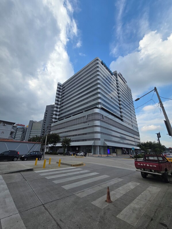 A modern multi-story hotel with a prominent 'Hilton' sign, a pedestrian crossing, and a parked red truck.