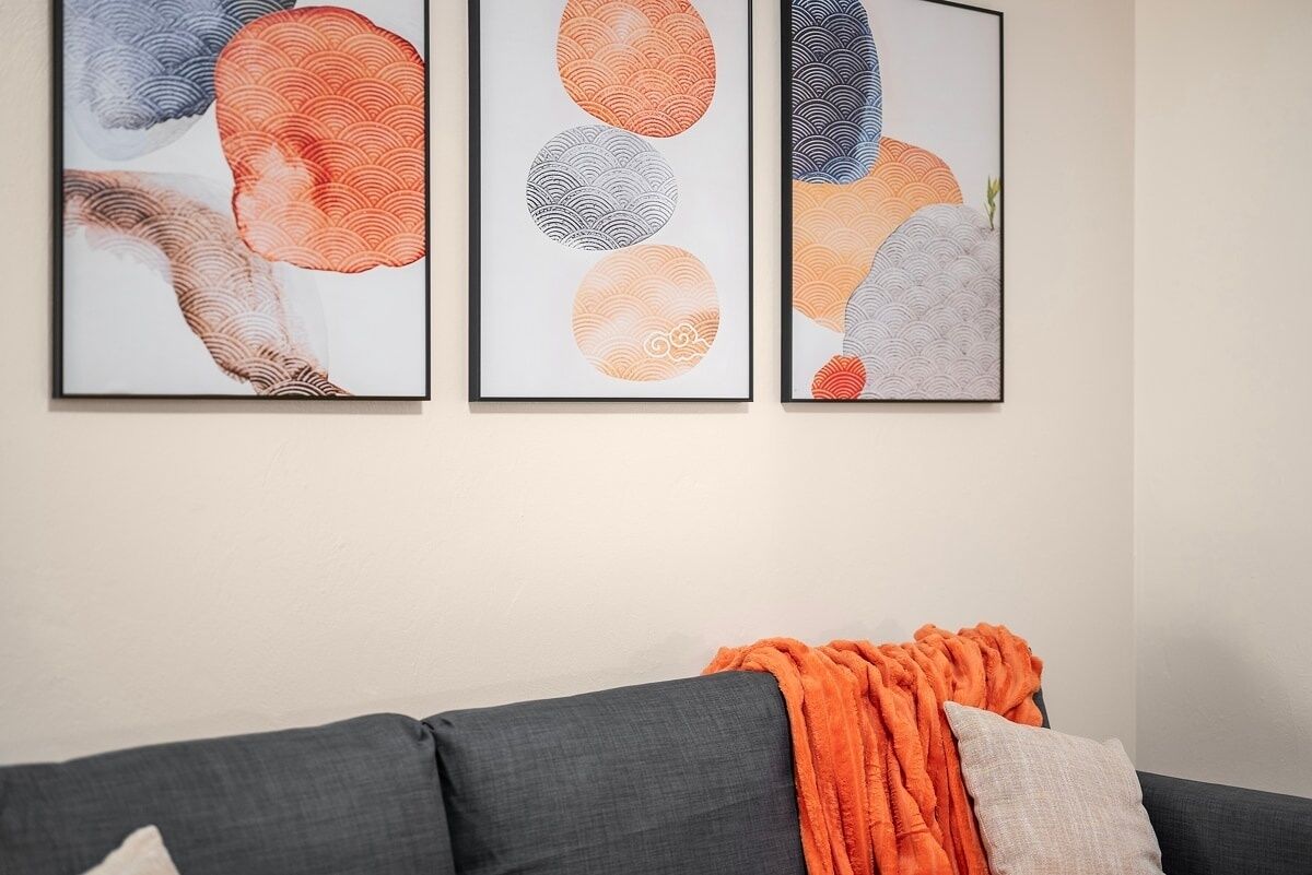 Een woonkamer met een grijze bank en een oranje plaid.