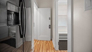 A narrow hallway with a refrigerator and a door leading to another room. - Modern 1 Bdr Apt unit#2 Sleeps4 (Pittsburgh)