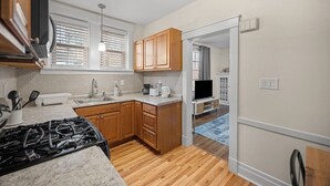 A compact kitchen with wooden cabinets, a stove, and a sink. - Modern 1 Bdr Apt unit#2 Sleeps4 (Pittsburgh)