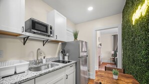 A modern kitchen with white cabinets, a granite countertop, a stainless steel refrigerator, and a microwave.