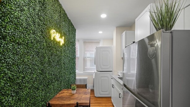 A modern kitchen with a green wall, a neon sign, and stainless steel appliances.