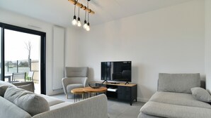 A modern living room with a sofa, armchair, and a TV on a stand.