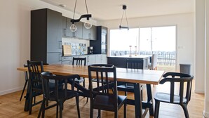 A modern kitchen with dark cabinets, a wooden dining table, and black chairs.
