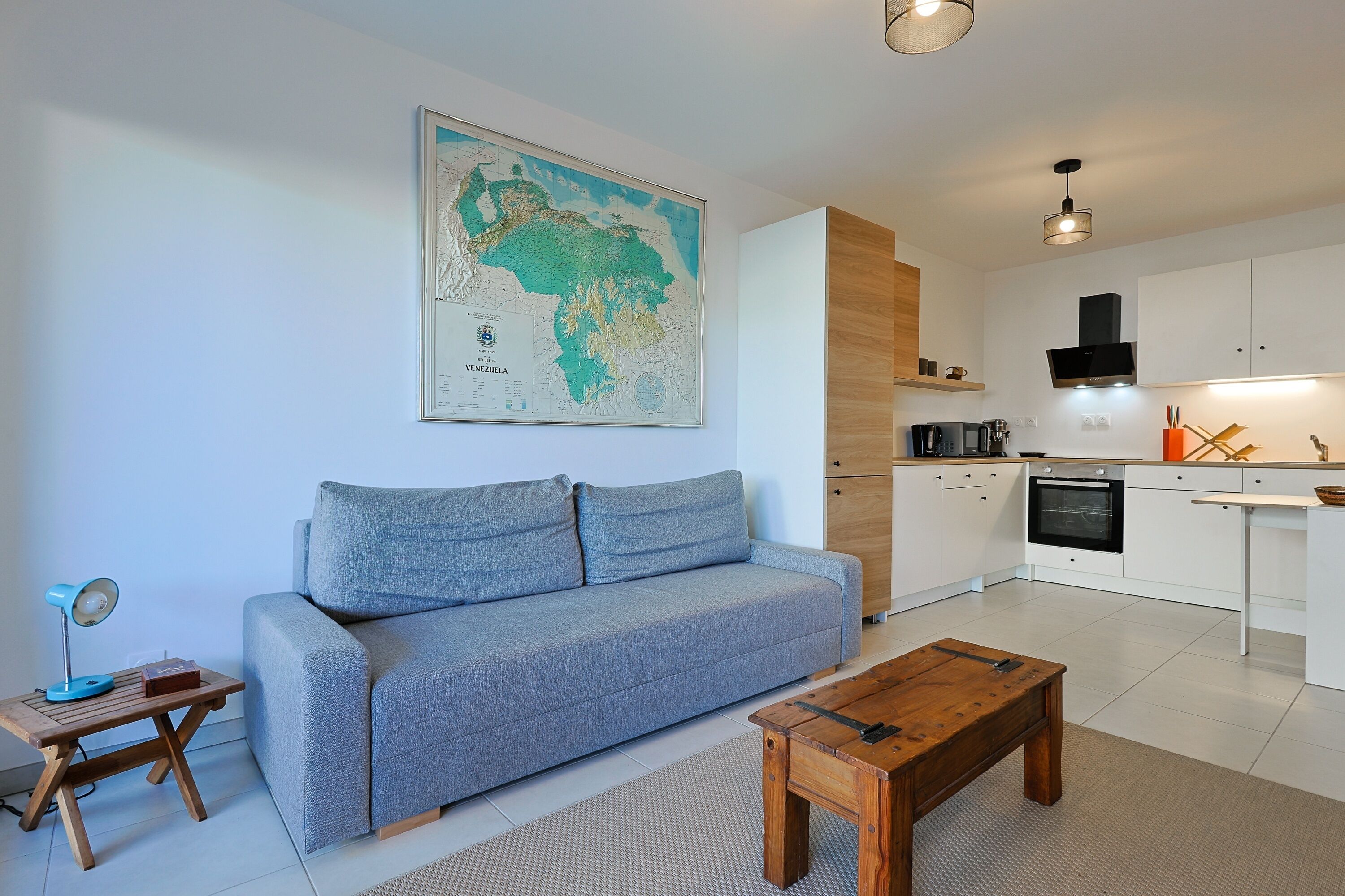 A modern living room with a grey sofa, wooden coffee table, and a map on the wall.