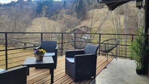 A wooden deck with wicker furniture and a table with a flower arrangement.