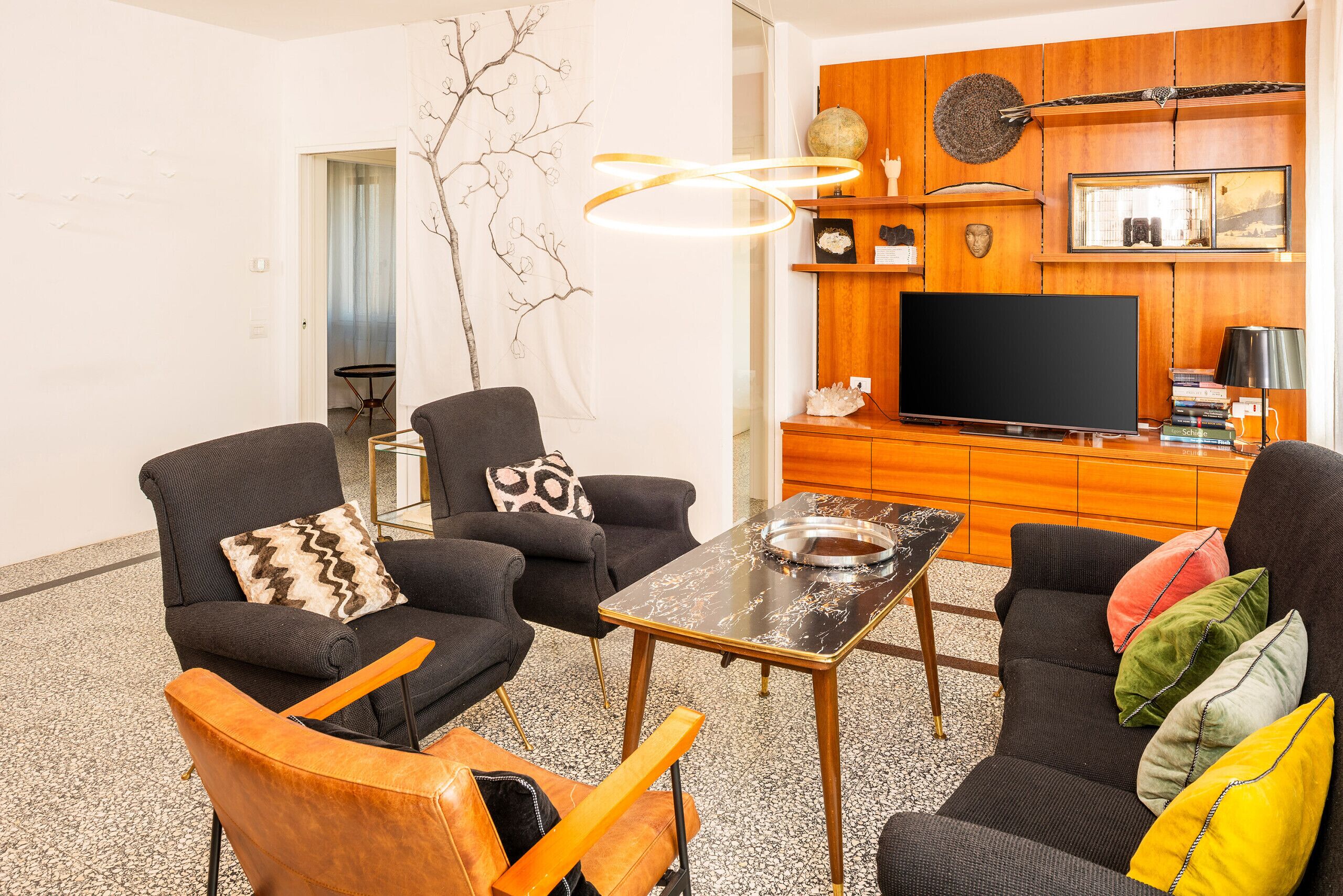 A modern living room with a flat-screen TV, two sofas, a coffee table, and a decorative wall piece.