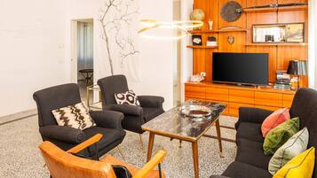 A modern living room with a flat-screen TV, two sofas, a coffee table, and a decorative wall piece.