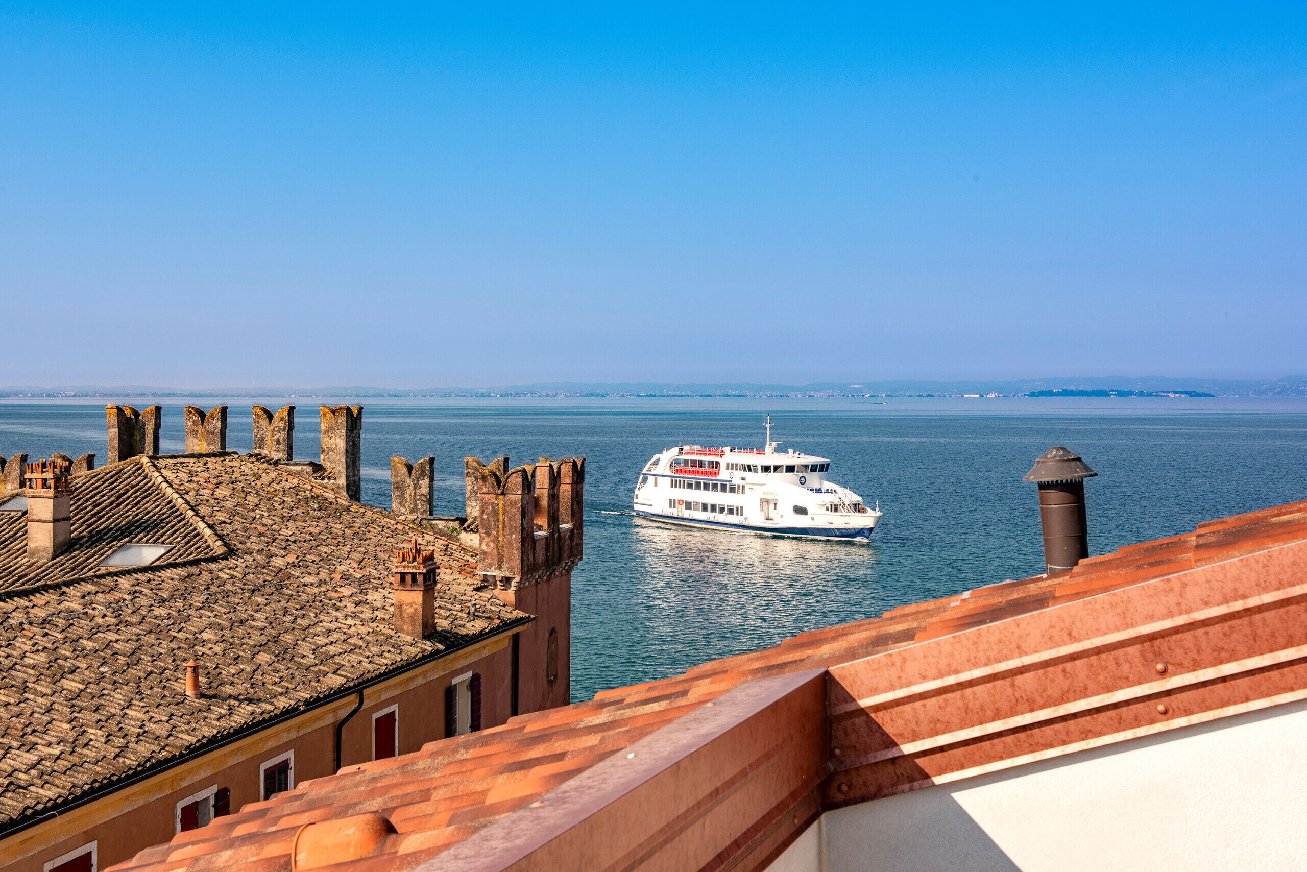 A coastal view with a historic building and a ferry in the water.
