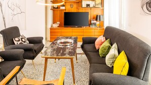 Una sala de estar moderna con un televisor de pantalla plana, dos sofás, una mesa de centro y un mueble de madera con estantes.