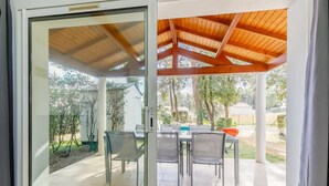Un patio cubierto con mesa y sillas, techo de madera y vistas del paisaje circundante.
