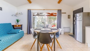 Una sala moderna con sofá, mesa de comedor, sillas y una cocina con refrigerador.