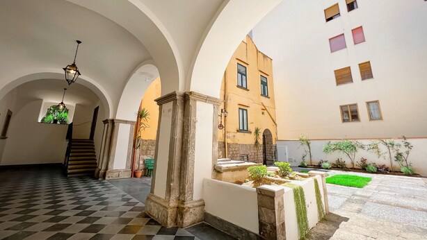 An interior courtyard with a checkered floor, arched ceilings, and a staircase leading to an upper level. - YourHome - Chiara's Apartment Sorrento 2 (Piano di Sorrento)