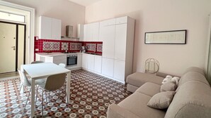 A compact living space with a kitchenette, a dining area, and a sofa. - YourHome - Chiara's Apartment Sorrento 2 (Piano di Sorrento)