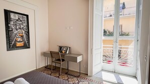 A hotel room with a bed, a desk, and a balcony with a view of the street. - YourHome - Chiara's Apartment Sorrento 2 (Piano di Sorrento)