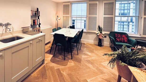 Una cocina moderna con comedor, una estantería empotrada y un amplio ventanal con contraventanas.