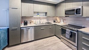 A modern kitchen with stainless steel appliances, a dishwasher, and a microwave. - Luxury Patio Suite + Pool + Gym + Lounge + Wi-Fi + Free Parking (Bellevue)