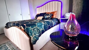 A modern bedroom with a bed, bedside table, and decorative lamp. - Luxury Patio Suite + Pool + Gym + Lounge + Wi-Fi + Free Parking (Bellevue)