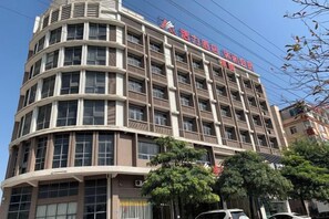 A multi-story hotel with a curved facade, large windows, and a sign indicating it is a hotel. - Charming Hotel (Heshan)