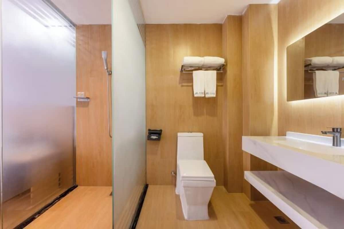 A modern bathroom with a wooden wall, a white toilet, a sink with a mirror, and a towel rack.