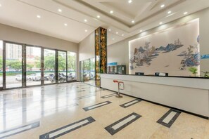 A hotel reception area with a large window, a reception desk, and a decorative wall.