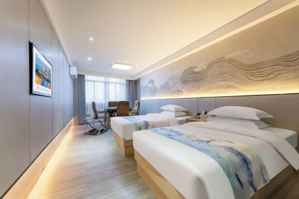 Ein modernes Hotelzimmer mit zwei Betten, einem Schreibtisch und einem Stuhl.
