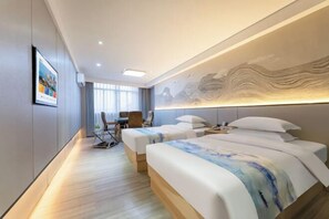 Ett modernt hotellrum med två sängar, ett skrivbord och en stol.