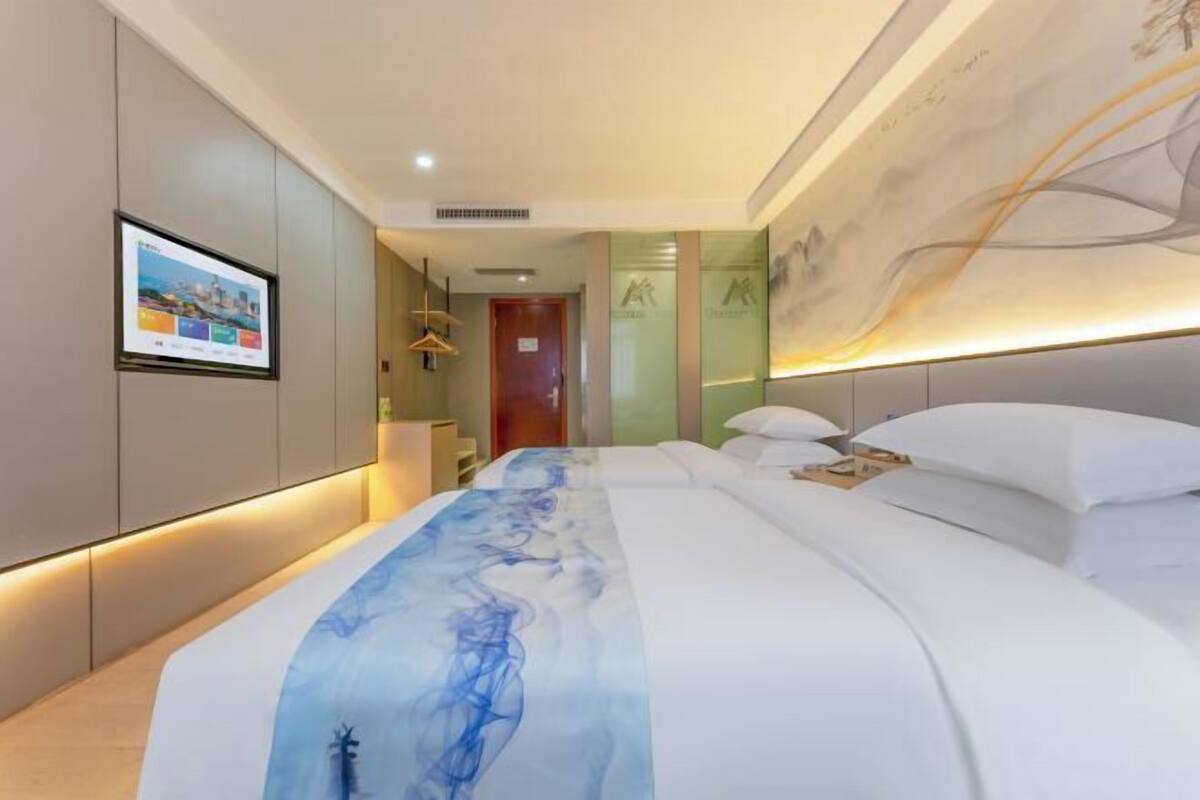 Ein modernes Hotelzimmer mit einem großen Bett, einem flachbildfernseher an der Wand und einem Wandgemälde an der Decke.