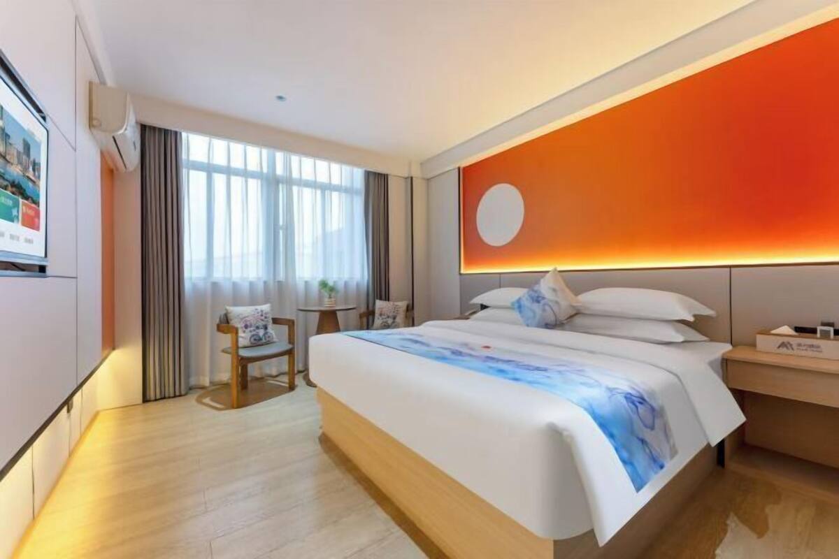 Ein Hotelzimmer mit einem großen Bett, einem Schreibtisch, einem Stuhl und einem an der Wand befestigten Fernseher.