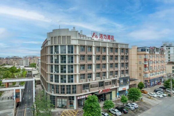 A multi-story building with a commercial ground floor, large windows, and a parking lot. - Charming Hotel (Heshan)