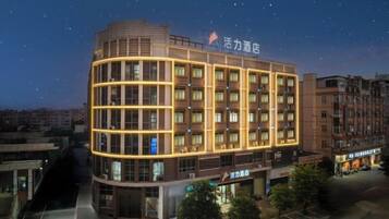 A multi-story hotel with a curved facade, illuminated windows, and a sign indicating it is a hotel.